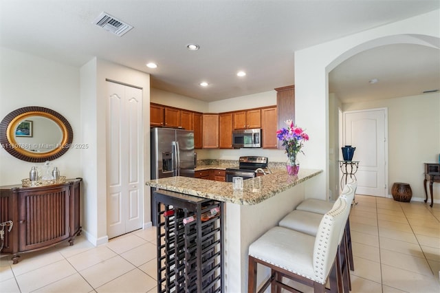 9618 Waterview Way, Parkland, FL 33076 - kitchen featuring stainless steel appliances, light tile patterned floors, arched walkways, a peninsula, and light stone counters