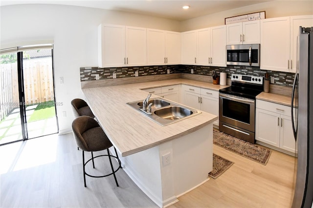 21068 NE 8th Ave, Miami, FL 33179 - kitchen with appliances with stainless steel finishes, a sink, a peninsula, light wood-style floors, and recessed lighting
