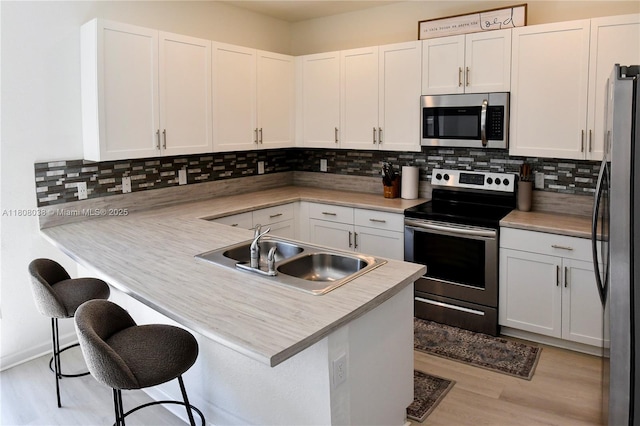 21068 NE 8th Ave, Miami, FL 33179 - kitchen with appliances with stainless steel finishes, a sink, tasteful backsplash, a peninsula, and white cabinetry
