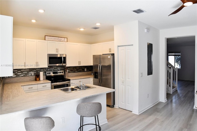 21068 NE 8th Ave, Miami, FL 33179 - kitchen with appliances with stainless steel finishes, a sink, a kitchen bar, tasteful backsplash, and light wood-style floors