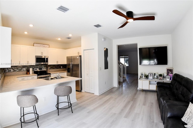 21068 NE 8th Ave, Miami, FL 33179 - kitchen featuring appliances with stainless steel finishes, open floor plan, a peninsula, a breakfast bar area, and backsplash