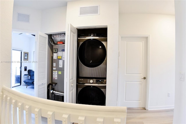 21068 NE 8th Ave, Miami, FL 33179 - laundry area with stacked washing machine and dryer, wood finished floors, water heater, and baseboards