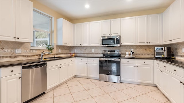 3945 Heron Ridge Ln, Weston, FL 33331 - kitchen featuring stainless steel appliances, a sink, dark countertops, decorative backsplash, and white cabinets