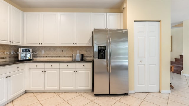 3945 Heron Ridge Ln, Weston, FL 33331 - kitchen featuring stainless steel refrigerator with ice dispenser, light tile patterned floors, dark countertops, decorative backsplash, and white cabinetry