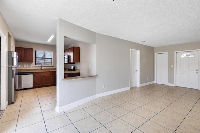 4960 NW 11th Ct, Lauderhill, FL 33313 - kitchen featuring appliances with stainless steel finishes, light tile patterned floors, a sink, a textured ceiling, and baseboards
