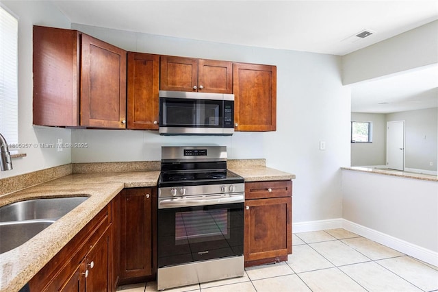 4960 NW 11th Ct, Lauderhill, FL 33313 - kitchen featuring stainless steel appliances, a sink, light tile patterned floors, baseboards, and light stone counters