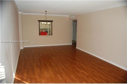 19390 Collins Ave Unit 217, Sunny Isles Beach, FL 33160 - unfurnished room with a chandelier, wood finished floors, crown molding, and baseboards