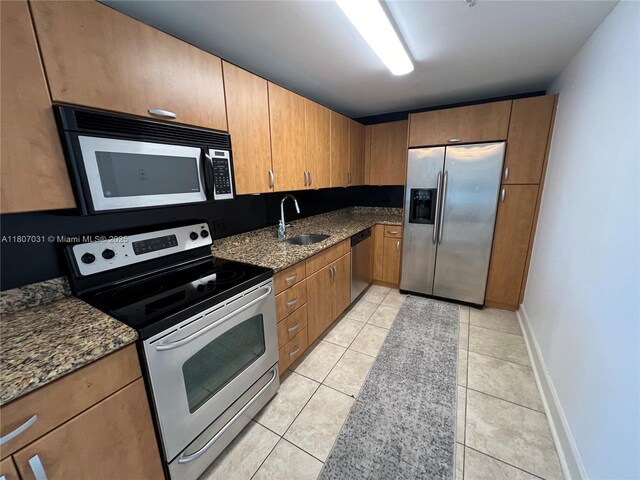 7501 E Treasure Dr Unit 9D, North Bay Village, FL 33141 - kitchen featuring appliances with stainless steel finishes, a sink, dark stone counters, light tile patterned floors, and baseboards