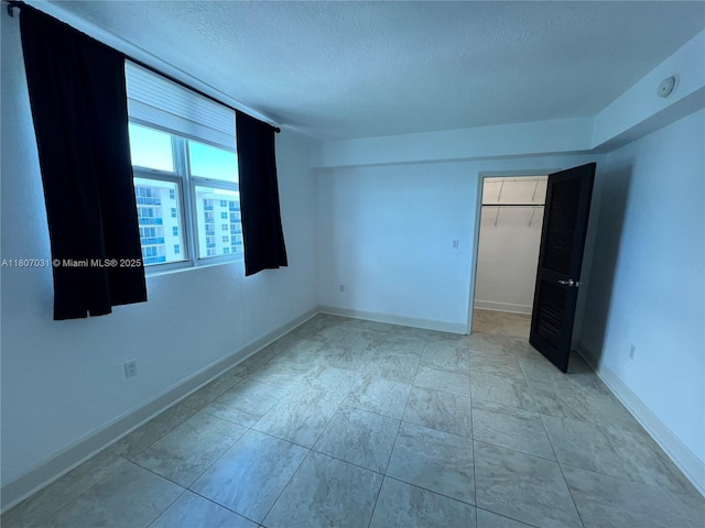 7501 E Treasure Dr Unit 9D, North Bay Village, FL 33141 - unfurnished bedroom with a textured ceiling, a walk in closet, baseboards, and a closet