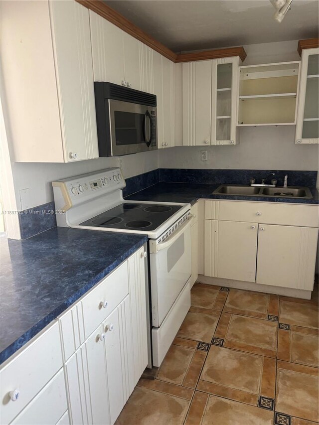 7850 Byron Ave Unit 403, Miami Beach, FL 33141 - kitchen with stainless steel microwave, white range with electric stovetop, dark countertops, glass insert cabinets, and open shelves