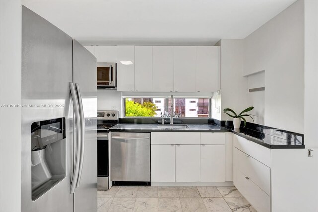 16919 N Bay Rd Unit 521, Sunny Isles Beach, FL 33160 - kitchen featuring appliances with stainless steel finishes, dark countertops, light marble finish flooring, white cabinetry, and modern cabinets