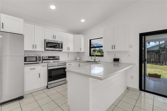 14234 SW 49th St, Miami, FL 33175 - kitchen with stainless steel appliances, vaulted ceiling, a sink, a peninsula, and light tile patterned floors