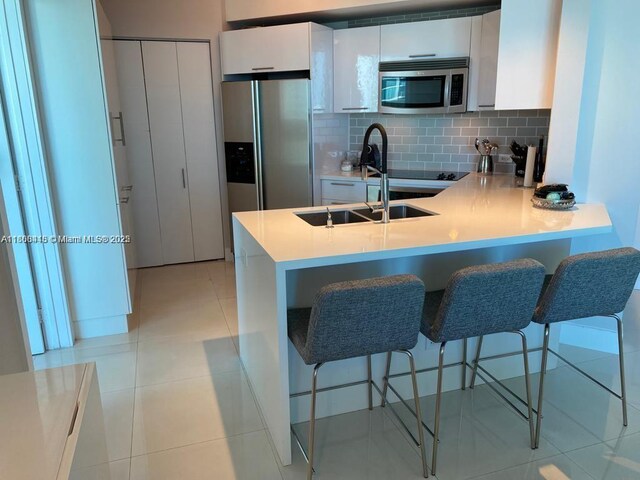 480 NE 30th St Unit 1405, Miami, FL 33137 - kitchen featuring appliances with stainless steel finishes, a peninsula, modern cabinets, white cabinetry, and tasteful backsplash