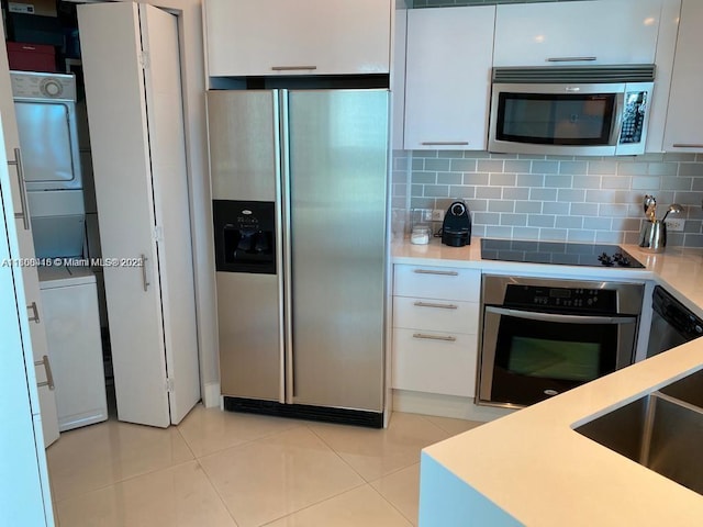 480 NE 30th St Unit 1405, Miami, FL 33137 - kitchen featuring appliances with stainless steel finishes, stacked washer / drying machine, a sink, white cabinetry, and light countertops