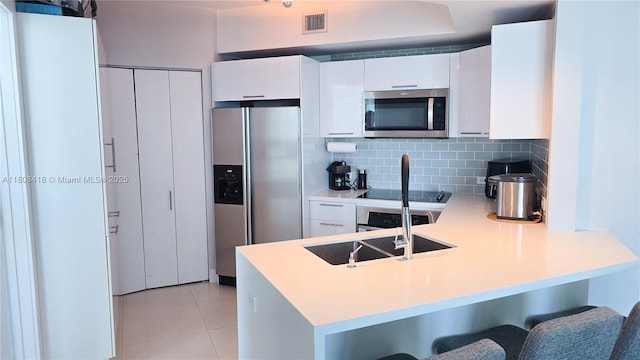 480 NE 30th St Unit 1405, Miami, FL 33137 - kitchen featuring stainless steel appliances, a peninsula, a kitchen breakfast bar, light tile patterned floors, and white cabinets