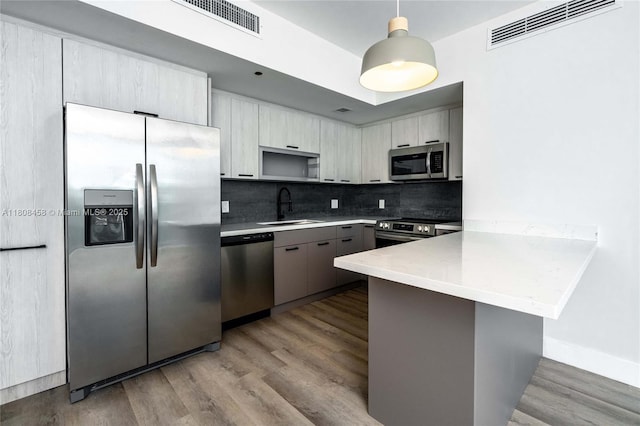 950 Brickell Bay Dr Unit 4007, Miami, FL 33131 - kitchen featuring appliances with stainless steel finishes, a sink, a peninsula, decorative backsplash, and wood finished floors