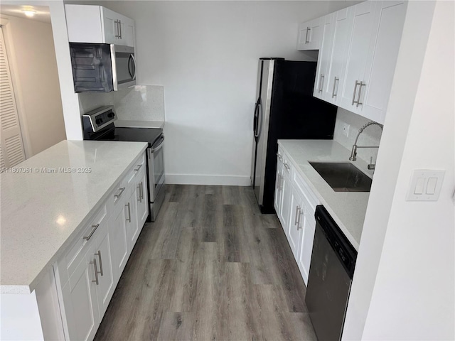 630 Layne Blvd Unit 211, Hallandale Beach, FL 33009 - kitchen with appliances with stainless steel finishes, wood finished floors, white cabinetry, light stone counters, and tasteful backsplash