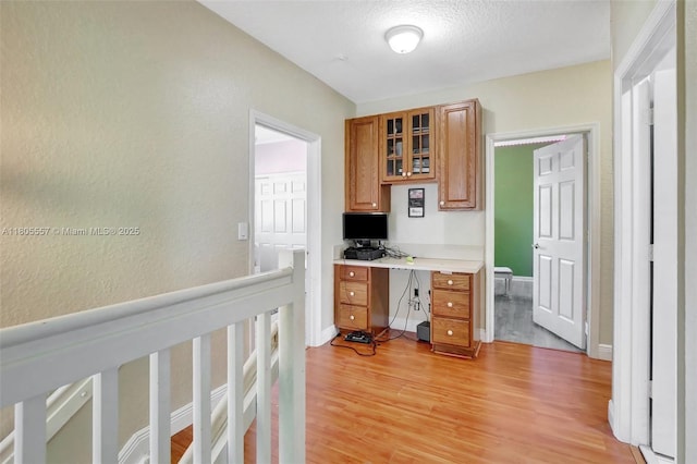 1874 NW 74th Way, Pembroke Pines, FL 33024 - kitchen featuring brown cabinets, light wood-style floors, glass insert cabinets, light countertops, and a textured wall