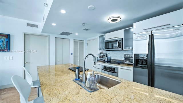 185 SW 7th St Unit 2911, Miami, FL 33130 - kitchen featuring stainless steel appliances, white cabinetry, light stone countertops, tasteful backsplash, and recessed lighting