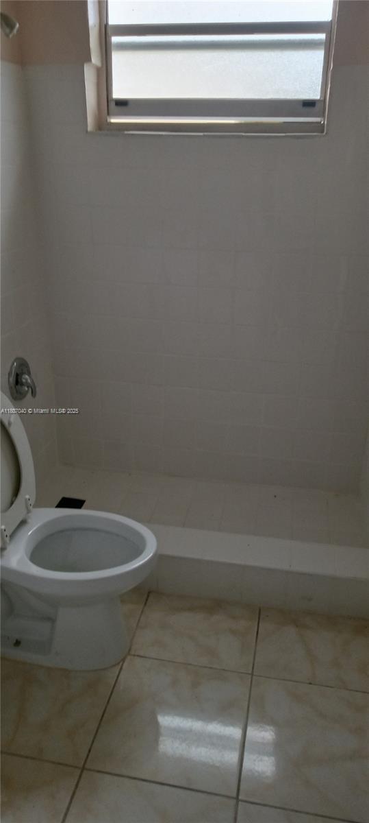 3161 NW 5th St, Lauderhill, FL 33311 - bathroom featuring toilet, tiled shower, and tile patterned floors