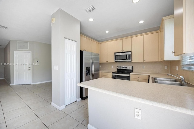 623 NE 21st Ter, Homestead, FL 33033 - kitchen featuring stainless steel appliances, a sink, light brown cabinets, a peninsula, and light countertops