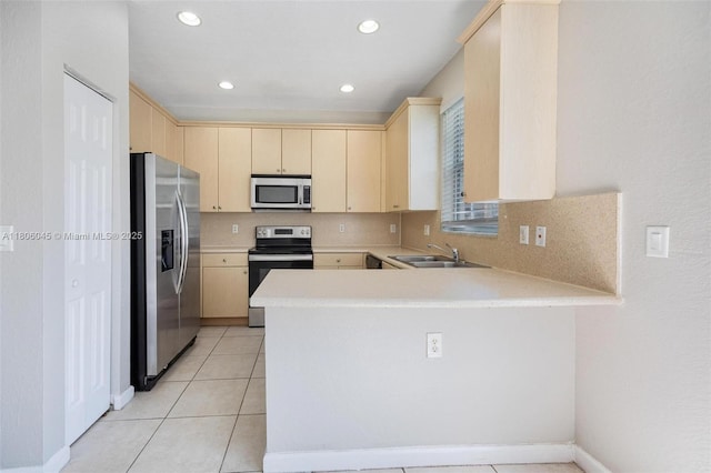 623 NE 21st Ter, Homestead, FL 33033 - kitchen with stainless steel appliances, a sink, a peninsula, light brown cabinetry, and light countertops