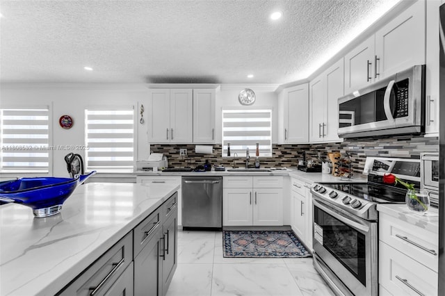 9304 SW 166th Ter, Palmetto Bay, FL 33157 - kitchen featuring appliances with stainless steel finishes, healthy amount of natural light, a textured ceiling, tasteful backsplash, and light stone countertops