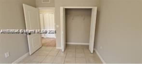 2903 SE 17th Ave Unit 102, Homestead, FL 33035 - unfurnished bedroom with a closet, light tile patterned floors, and baseboards