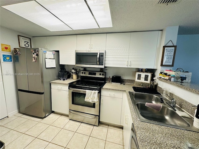 5031 Wiles Rd Unit 304, Coconut Creek, FL 33073 - kitchen with stainless steel appliances, a sink, white cabinetry, and light tile patterned floors