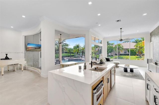 10881 Hawks Vista St, Plantation, FL 33324 - kitchen featuring a sink, ornamental molding, ceiling fan, oven, and a kitchen island with sink