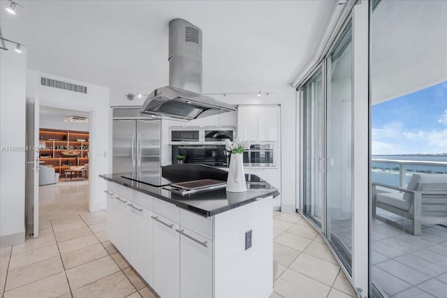 2127 Brickell Ave Unit 2302, Miami, FL 33129 - kitchen featuring island range hood, dark countertops, stainless steel built in refrigerator, light tile patterned floors, and white cabinets