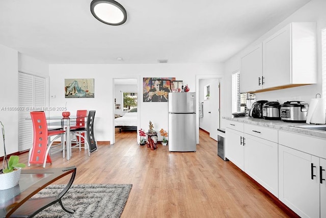 12400 NE 11th Ct, North Miami, FL 33161 - kitchen featuring freestanding refrigerator, light wood-type flooring, light countertops, and white cabinetry