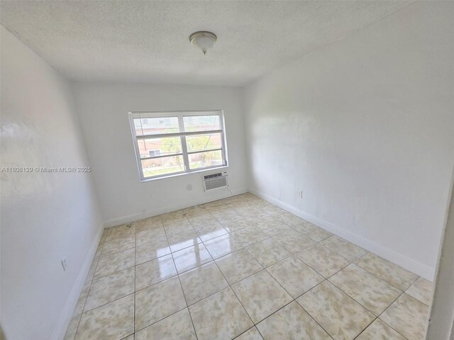3621 SW 10th St Unit 4B, Miami, FL 33135 - spare room featuring a textured ceiling, light tile patterned flooring, a wall mounted air conditioner, and baseboards