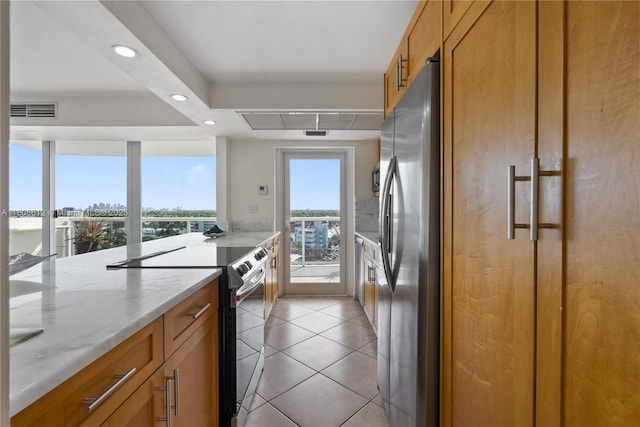 2841 N Ocean Blvd Unit 1105, Fort Lauderdale, FL 33308 - kitchen with range with electric cooktop, freestanding refrigerator, brown cabinetry, light stone counters, and recessed lighting
