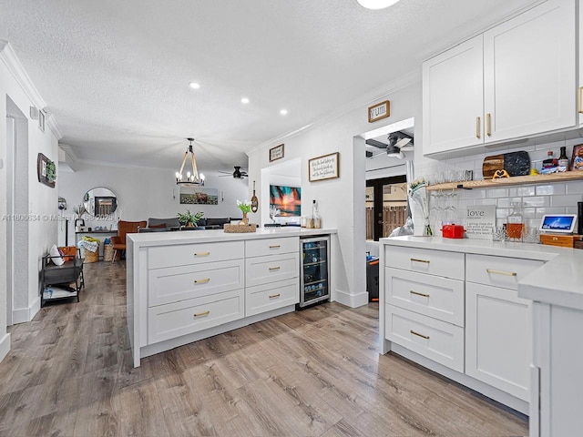 12749 SW 71st Ter, Miami, FL 33183 - kitchen featuring wine cooler, crown molding, light countertops, light wood-style floors, and white cabinets
