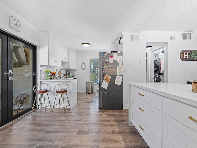12749 SW 71st Ter, Miami, FL 33183 - kitchen with freestanding refrigerator, stacked washer / drying machine, ornamental molding, white cabinetry, and light countertops