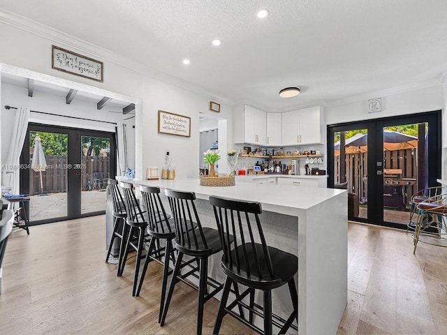 12749 SW 71st Ter, Miami, FL 33183 - kitchen featuring french doors, light wood-style floors, white cabinets, a breakfast bar area, and crown molding