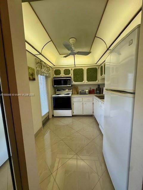 700 NE 14th Ave Unit 204, Hallandale Beach, FL 33009 - kitchen with white appliances, a ceiling fan, light countertops, white cabinetry, and glass insert cabinets