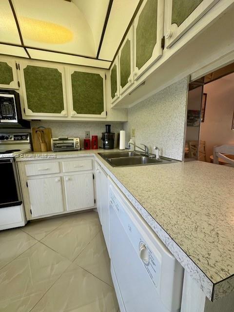 700 NE 14th Ave Unit 204, Hallandale Beach, FL 33009 - kitchen featuring white appliances, light countertops, a sink, glass insert cabinets, and white cabinetry