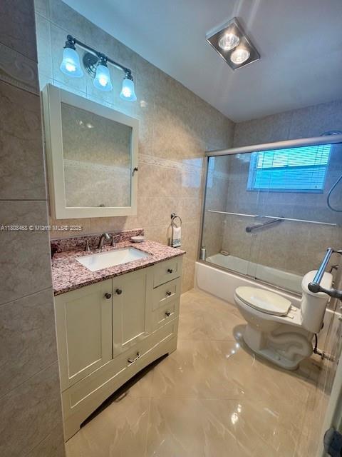 700 NE 14th Ave Unit 204, Hallandale Beach, FL 33009 - bathroom with tile walls, toilet, bathtub / shower combination, vanity, and marble finish floors
