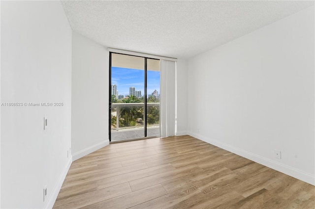 20185 E Country Club Dr Unit 505, Aventura, FL 33180 - spare room with floor to ceiling windows, a textured ceiling, light wood finished floors, baseboards, and a skyline view