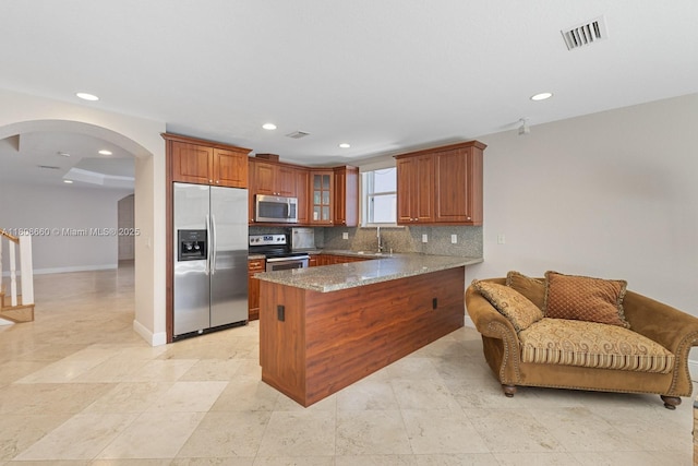 2922 Catalina St Unit 2922, Miami, FL 33133 - kitchen with stainless steel appliances, a sink, a peninsula, brown cabinetry, and recessed lighting