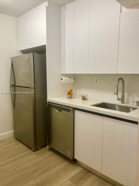 200 NW 107th Ave Unit 106, Miami, FL 33172 - kitchen with appliances with stainless steel finishes, a sink, white cabinetry, light wood finished floors, and light countertops