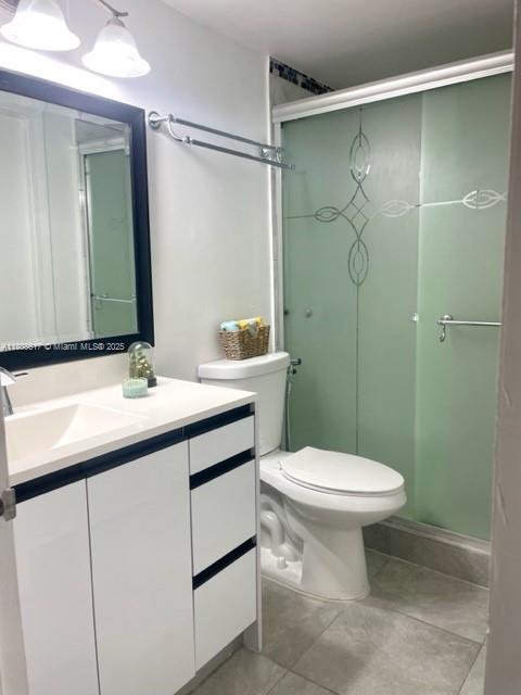 200 NW 107th Ave Unit 106, Miami, FL 33172 - full bathroom featuring vanity, toilet, a stall shower, and tile patterned flooring