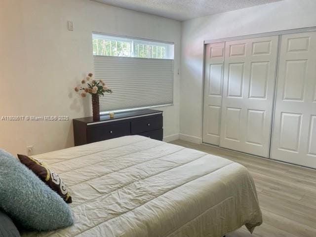 200 NW 107th Ave Unit 106, Miami, FL 33172 - bedroom with wood finished floors, a closet, a textured ceiling, and baseboards