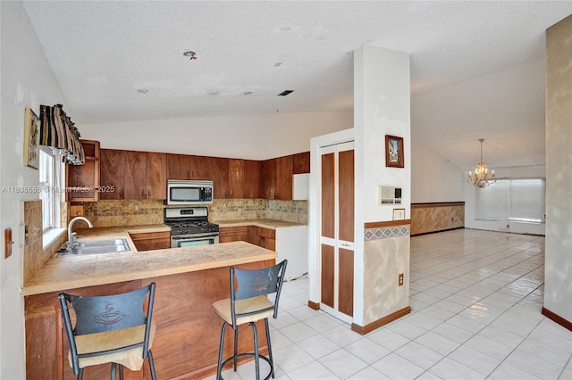 8749 NW 189th Ter, Hialeah, FL 33018 - kitchen with stainless steel appliances, a sink, lofted ceiling, a chandelier, and light countertops