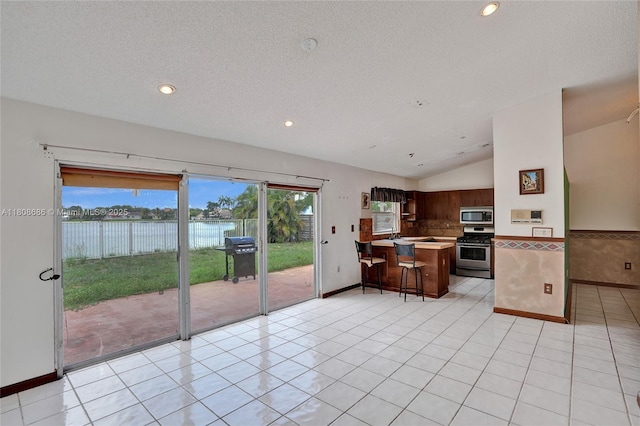 8749 NW 189th Ter, Hialeah, FL 33018 - kitchen featuring stainless steel appliances, lofted ceiling, a water view, a breakfast bar, and light countertops