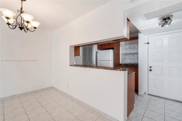 11604 NW 11th St, Pembroke Pines, FL 33026 - kitchen featuring freestanding refrigerator, light tile patterned flooring, a peninsula, a chandelier, and pendant lighting