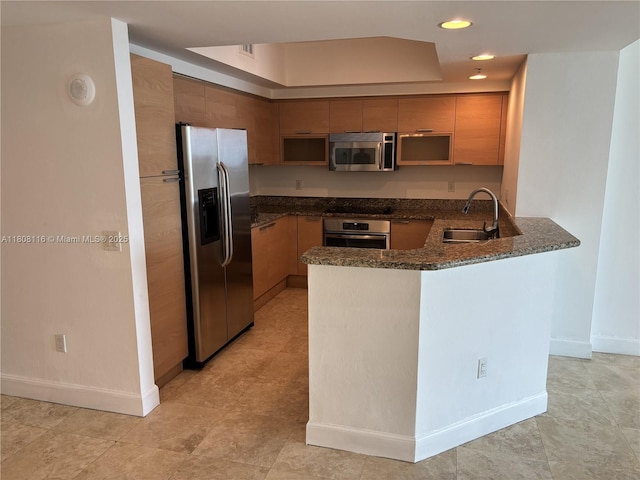 15051 Royal Oaks Ln Unit 1604, North Miami, FL 33181 - kitchen featuring stainless steel appliances, a peninsula, a sink, dark stone countertops, and baseboards