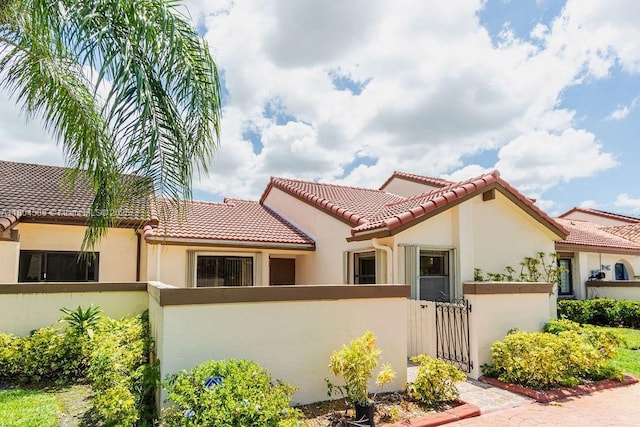 17359 NW 66th Ct, Hialeah, FL 33015 - mediterranean / spanish-style home with a fenced front yard, stucco siding, a tiled roof, and a gate